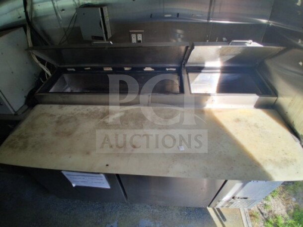2019 Quality Cargo Food Trailer interior with refrigeration suite, grease hood, and countertop. Signs of wear visible.