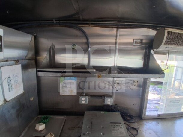 Interior view of a 2019 Quality Cargo food trailer. Features include grease hood, dual fryers, griddle, and refrigeration suite.