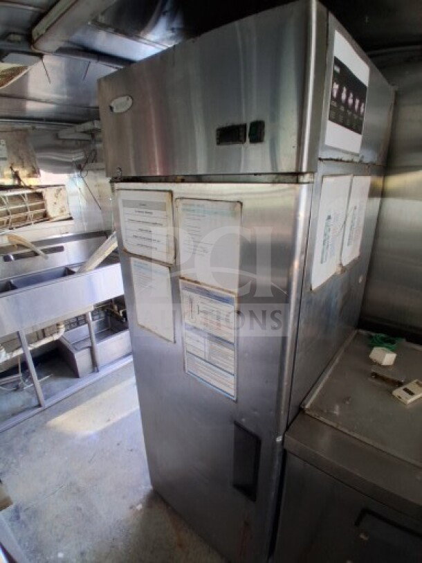 2019 Quality Cargo Food Trailer interior showing stainless steel refrigerator with attached documents, fryers, and griddle.