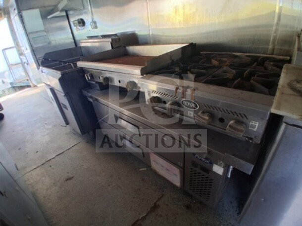 2019 Quality Cargo food trailer interior with griddle, dual fryers, burner cooktop, grease hood, and refrigeration units.