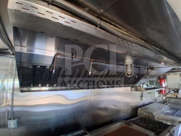 2019 Quality Cargo Food Trailer interior, featuring a commercial-grade grease hood, dual fryers, griddle, and burner cooktop.