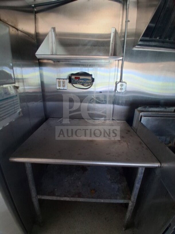 2019 Quality Cargo food trailer interior, stainless steel counter, overhead shelf, electrical outlets, and visible grease hood.