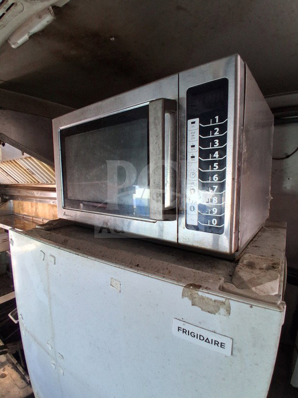 Microwave on a Frigidaire reach-in freezer inside 2018 Freedom 20' food trailer, showing control panel and visible wear.