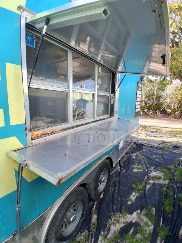 2018 Freedom 20' food trailer with large service window, shown open. Dual-axle with visible wear. Ideal for high-volume events.