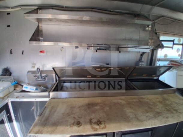 2018 Freedom 20' Food Trailer interior with stainless steel shelving, cooking line, sink, and refrigeration units, showcasing professional-grade kitchen equipment.