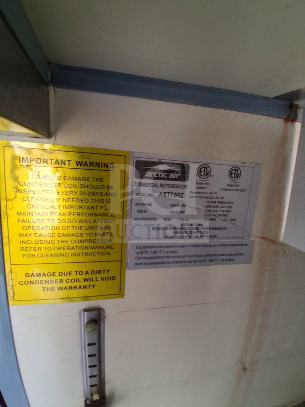 Tags on the Arctic Air commercial refrigerator model AST72RZ are shown, displaying maintenance warnings and specifications.
