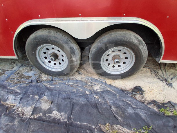 Red 2021 Haulmark 8.5' x 24' dual-axle mobile kitchen trailer tires and wheels, exterior view.