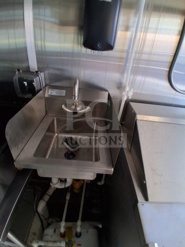 2021 Diamond Cargo 24' mobile kitchen sink area, stainless steel, with visible pipes and soap dispenser.