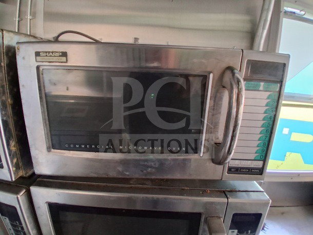 Sharp commercial microwave oven in used condition, featuring a digital keypad and stainless steel exterior.