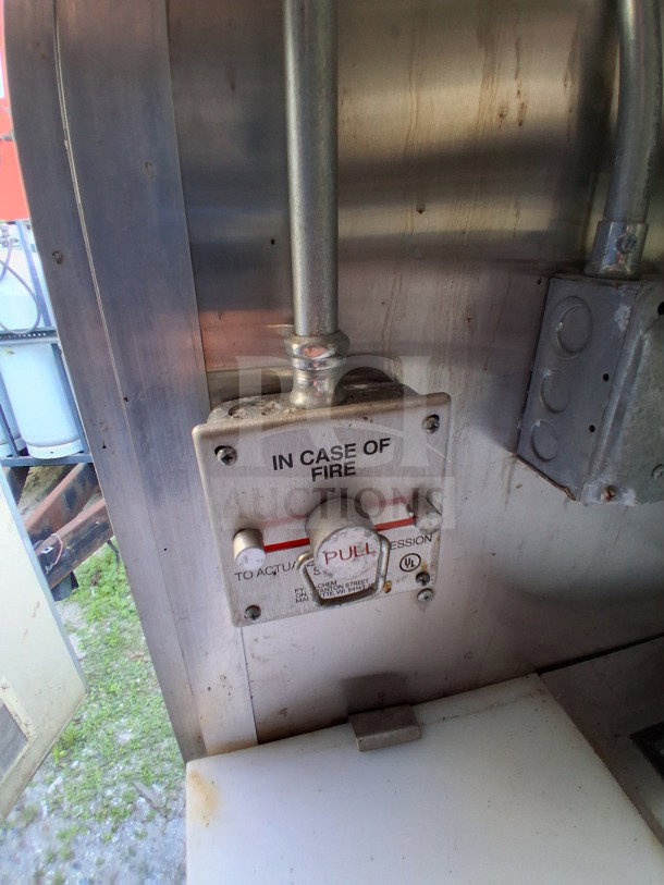 Fire suppression activation switch inside a 2021 Diamond Cargo 24' Custom Mobile Kitchen, featuring stainless steel interior.