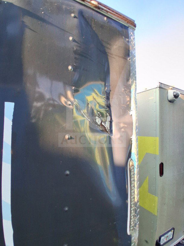 Damaged exterior of 2019 Quality Cargo Food Trailer, showing a large dent and tear.