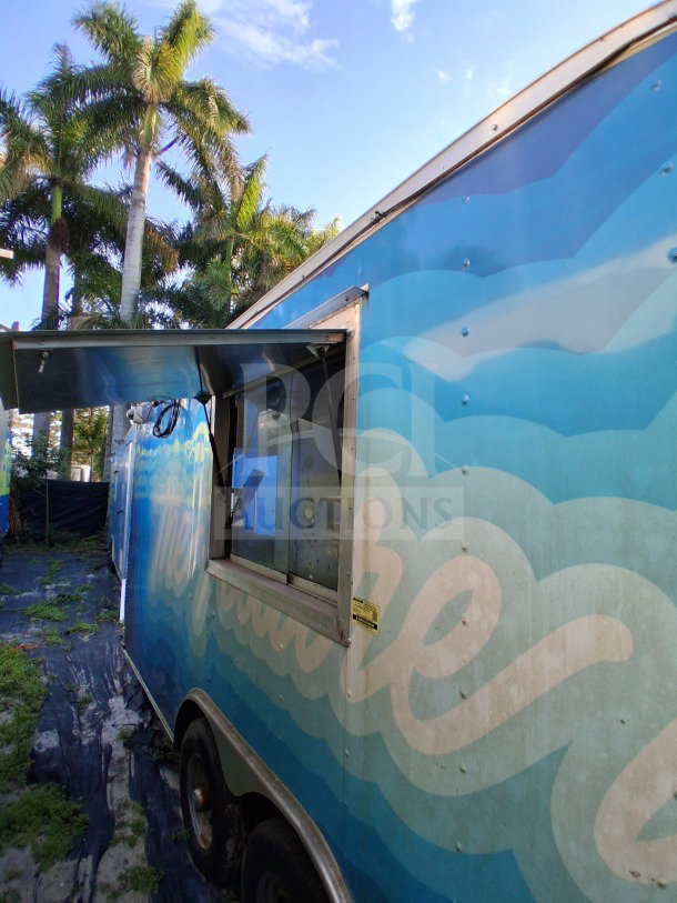 2019 Quality Cargo Food Trailer with large order window, equipped with grease hood, dual fryers, griddle, burner cooktop.