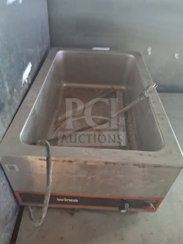 Large stainless steel commercial food warmer, branded Winco, in used condition with visible wear and attached power cord.