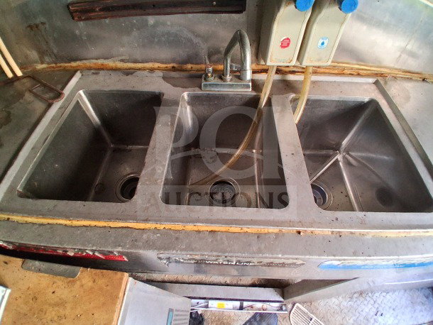 2019 Quality Cargo food trailer interior with triple sink units, visible wear, equipped for commercial use.