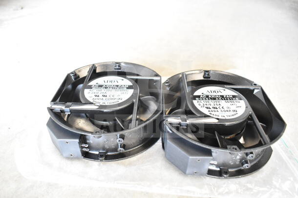 Two black ADDA AC axial fans, model LA151BH, 100-120V, Made in Taiwan, displayed on a clear surface.