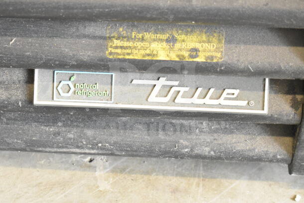 True GDM-72F-HC label showing "natural refrigerant" logo, used merchandise freezer in dusty condition.