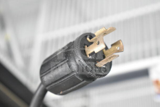 Close-up of the power plug for a 2020 True GDM-72F-HC Commercial Freezer. Three-prong design, black casing, metal prongs.