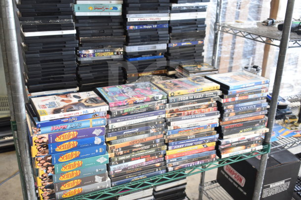 Collection of 340 various DVDs, including 8 Mile, Catch Me If You Can, The Simpsons; good condition on metal shelves.