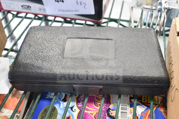 Black textured hard case on shelf containing tools. Auction labels visible, promising 4 times bid value.