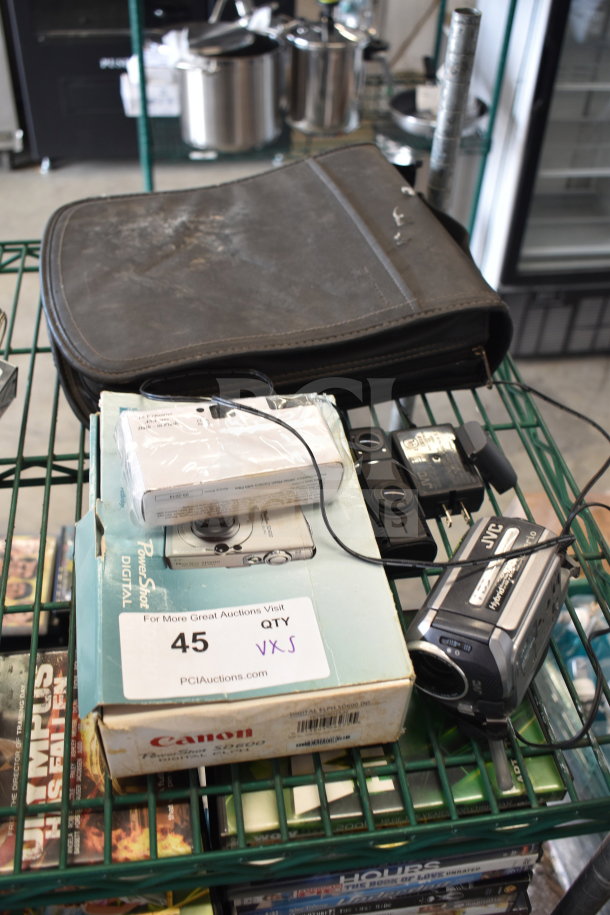 5-item lot includes Canon PowerShot digital camera and JVC camcorder. Items show signs of wear. Boxed camera has label: "For More Great Auctions Visit."