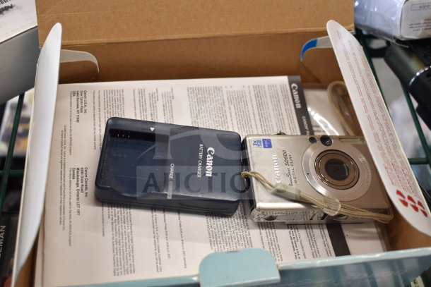5 various items in an open box, featuring a Canon PowerShot SD600 Digital ELPH camera and Canon battery charger.