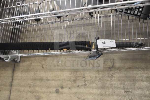 Samurai sword in black sheath with intricate hilt design on metal shelf. Tag reads "46" for auction listing.