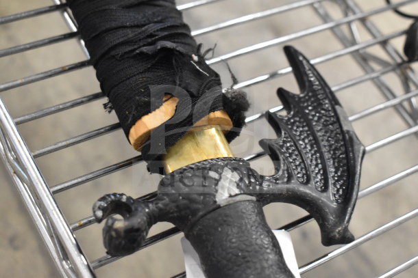 Samurai sword in sheath with a dragon-themed hilt, black grip wrap, minor wear on handle, stored on a metal rack.