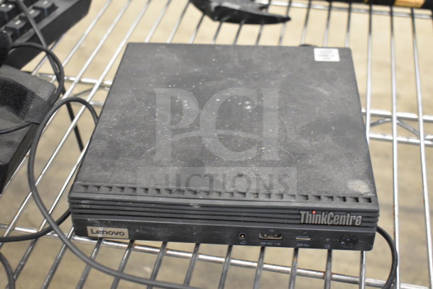Lenovo ThinkCentre desktop computer, visible dust, located on a metal rack, with ports and branding shown.
