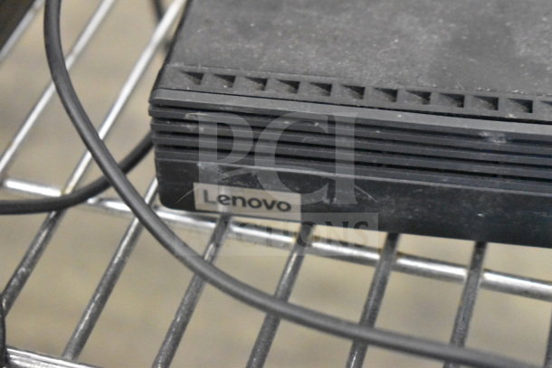 Lenovo ThinkCentre, black casing, visible label, resting on metal rack, part of auction bundle.