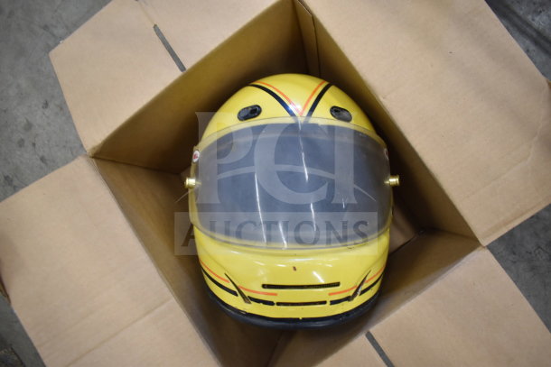 Yellow Simpson VN 6-7/8 helmet with clear visor, placed in a cardboard box. Features racing stripes and vent detail.