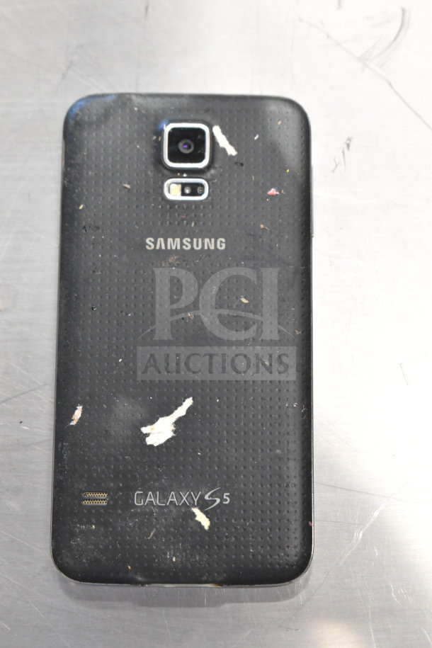 Samsung Galaxy S5 smartphone, black with visible wear and scratches on the back.