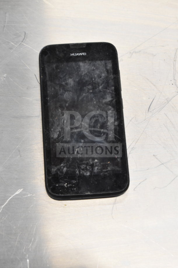 Huawei smartphone with visible wear and scratches, displayed on a metal surface.
