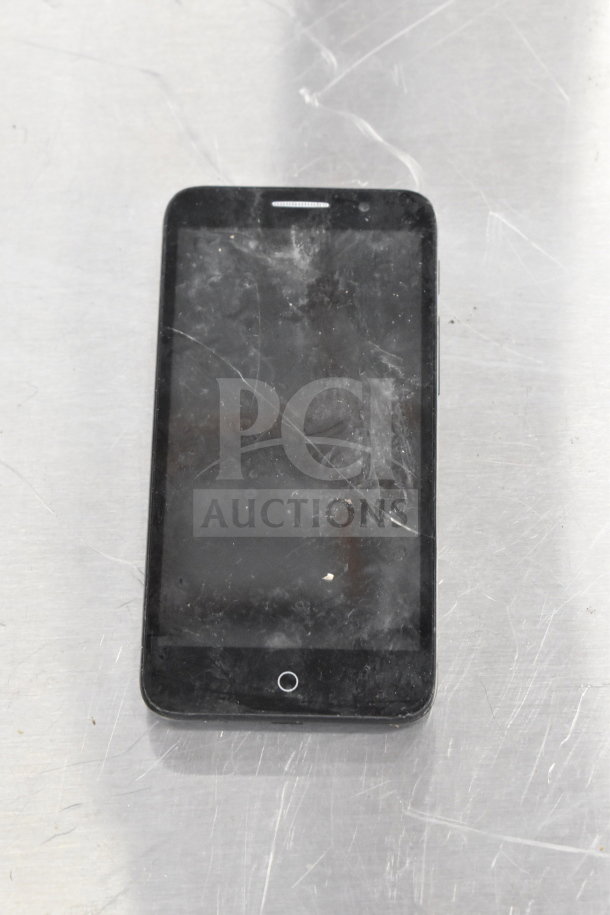 Smartphone with visible wear, scratches on screen, and a single circular button. Part of an 8-item auction lot.