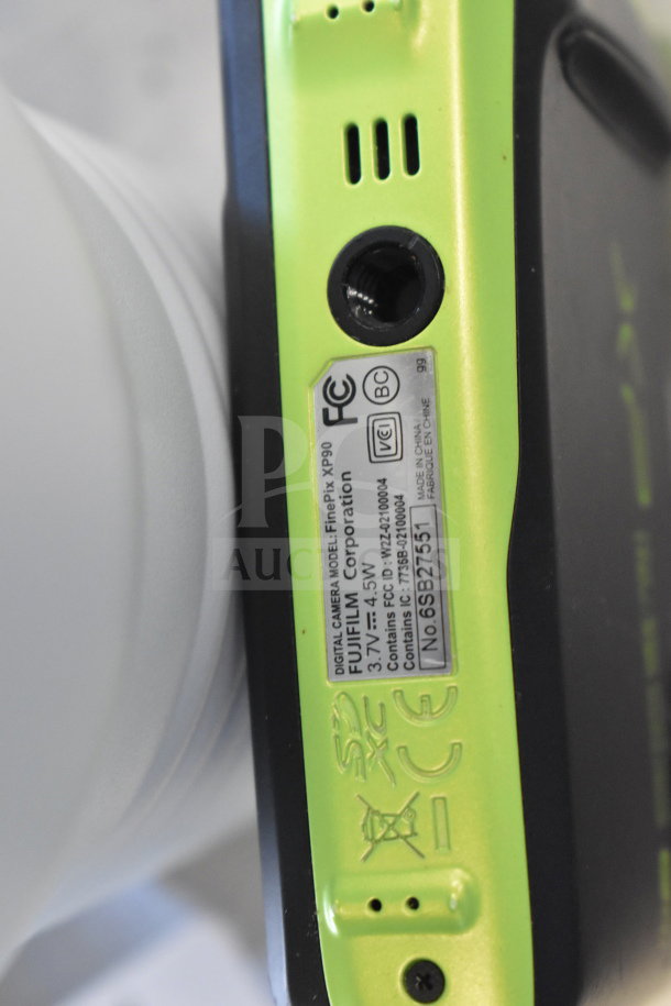 Close-up of a green Fujifilm FinePix XP90 digital camera label indicating model and specifications.