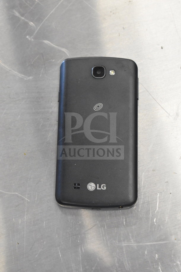 LG smartphone with rear camera and flash on stainless steel surface, visible logo and emblem, part of auction lot.