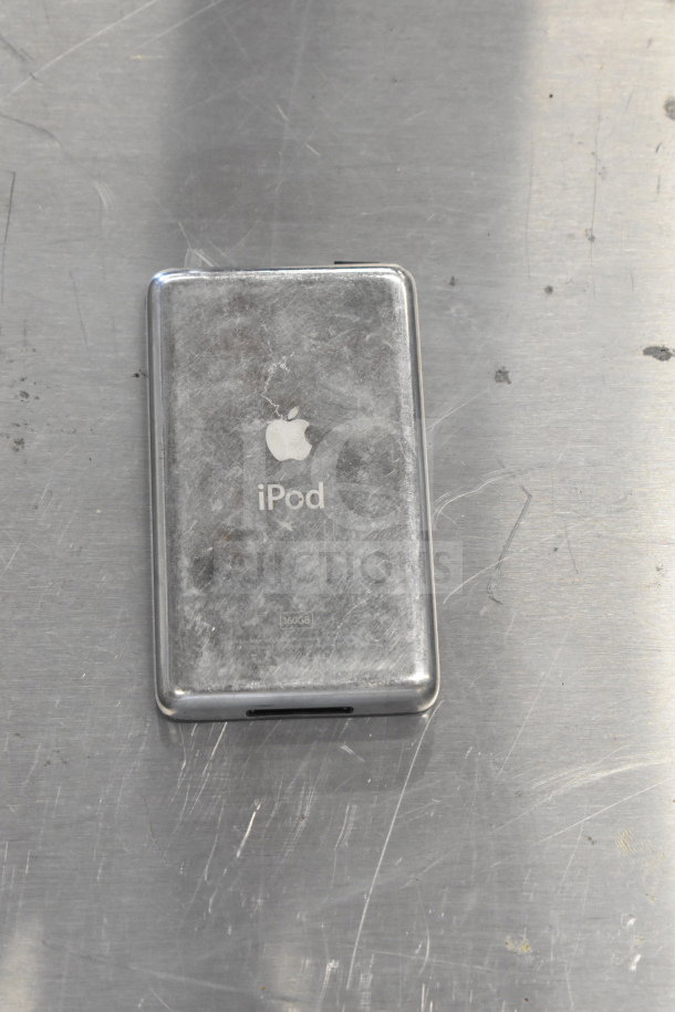 Worn Apple iPod with silver back, engraved Apple logo and "iPod." Visible scratches on a metallic surface.