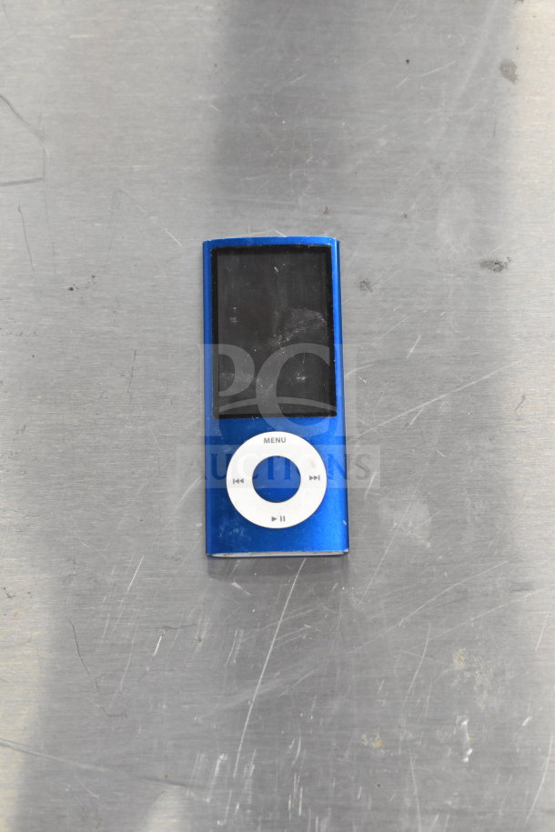 Blue iPod Nano with visible scratches, circular control pad, and black display screen. Auction includes 8 various tech items.