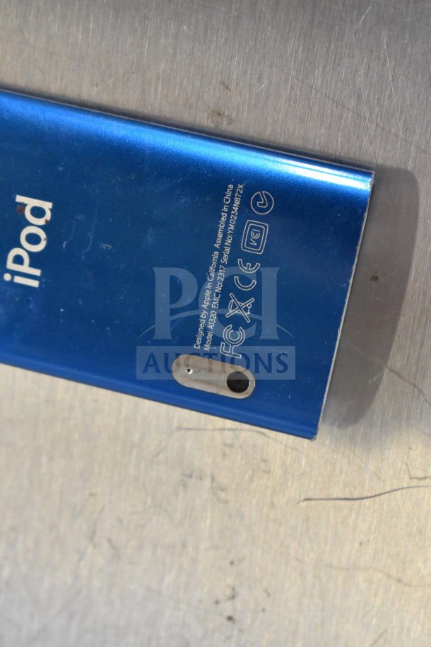 Blue Apple iPod, Model A1320, with visible branding and regulatory markings. Includes variety of 8 tech items.