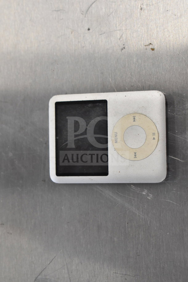 Old model iPod with click wheel, silver color, in used condition with visible wear. Auction includes 8 various items.