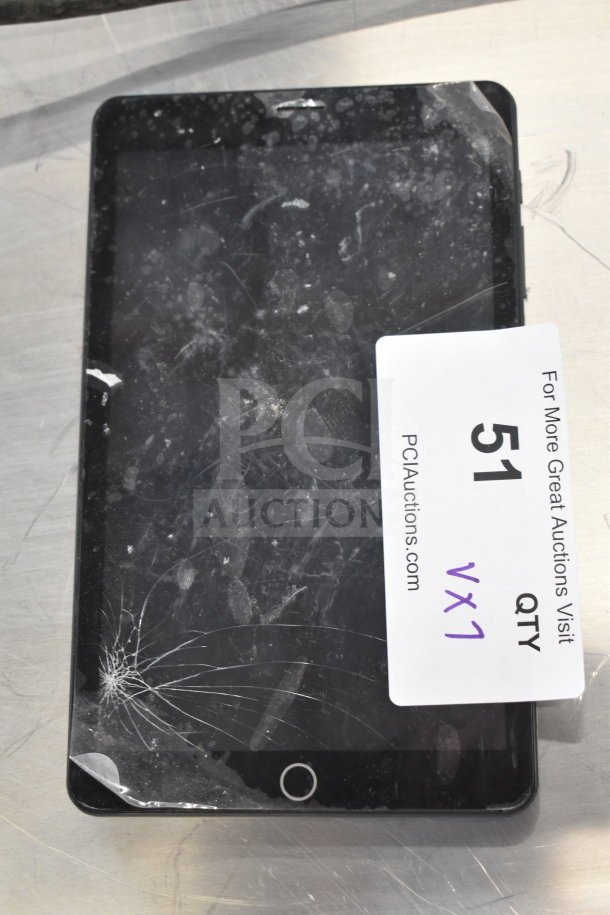 Damaged tablet with cracked screen, visible label reading "51 QTY VX1," part of a lot including Genesis portable player.