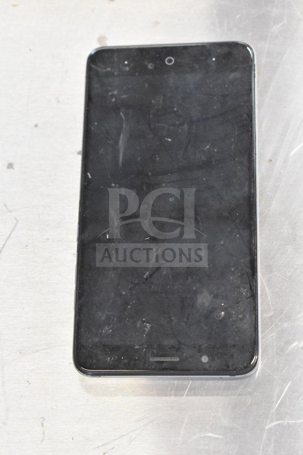 Black smartphone with a sleek design, showing signs of use. Part of a lot including Genesis Ultimate Portable Game Player.