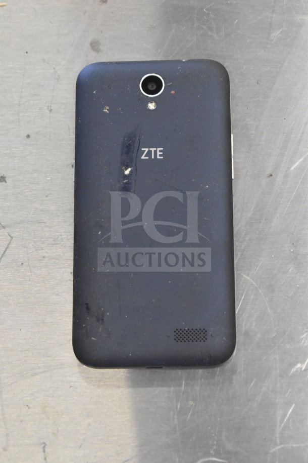 ZTE smartphone with minor surface wear, visible logo. Part of a lot including Genesis Ultimate Portable Game Player, 3 smartphones.