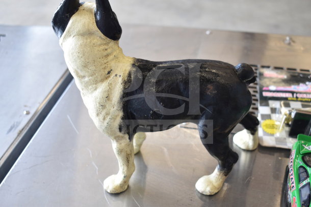 Dog-shaped piggy bank with black and white paint, showing wear. Includes Hot Wheels and die-cast car packages.