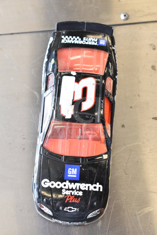 Die-cast car with "Goodwrench Service Plus" branding, black and red color scheme, visible wear. Auction includes five other items.