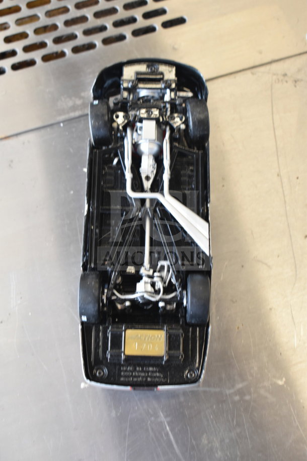 Underside view of a die-cast car model with detailed mechanical features and an "Action 1704" marking.