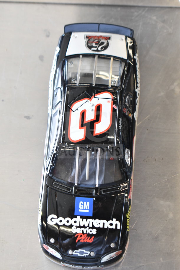 Die-cast model car featuring Goodwrench Service Plus branding, black with red and white details, GM logo on hood.