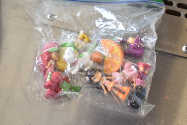 Bag of 15 assorted toys, including Cinderella doll, Tamagotchi, Strawberry Shortcake figurines, dinosaur, sanitizer cozies.