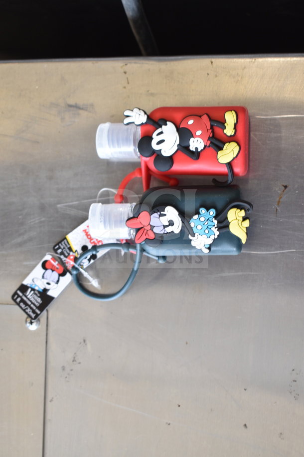 Two Mickey Mouse-themed hand sanitizer cozies, new, with attached tags, featuring cute character designs.