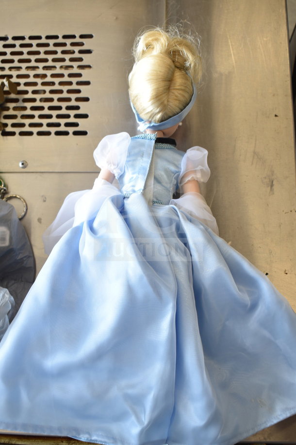 Blonde Cinderella doll in a blue dress on a metallic surface; part of a mixed lot of 15 items including figurines and toys.