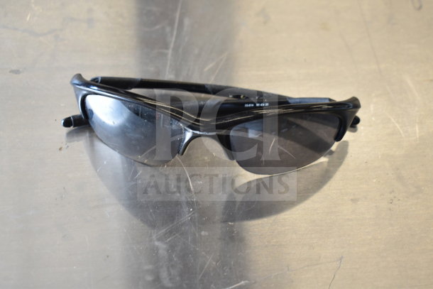 Black sunglasses with reflective lenses, part of an auction lot including watches and a fitness watch. Good condition.